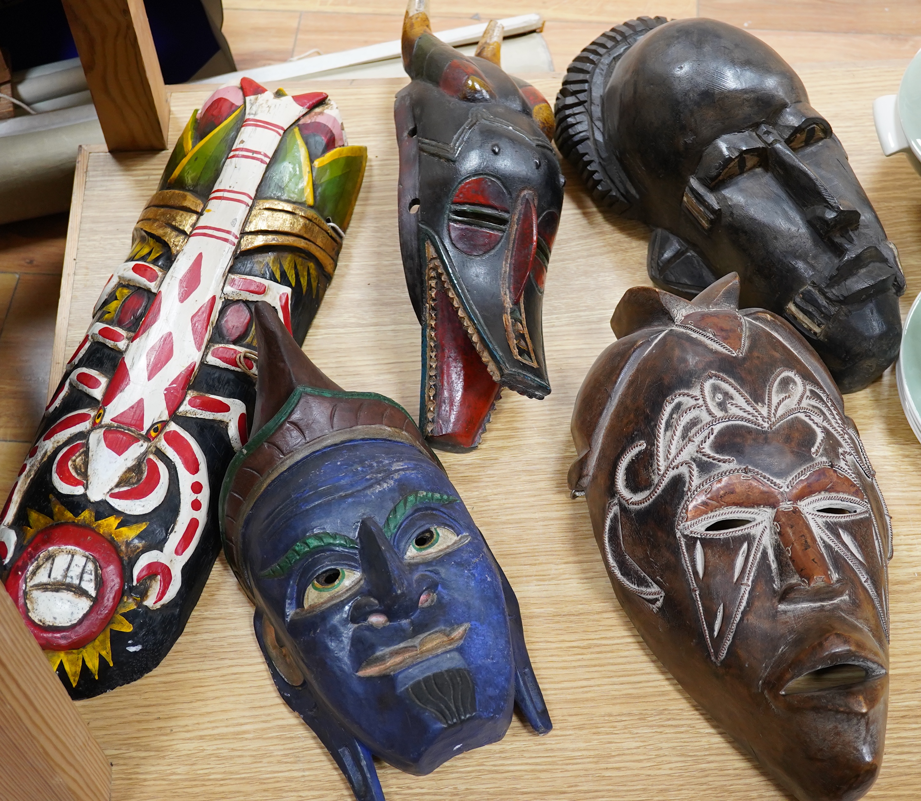 Five various tribal masks and a chip carved panel, 100x45cm. Condition - good